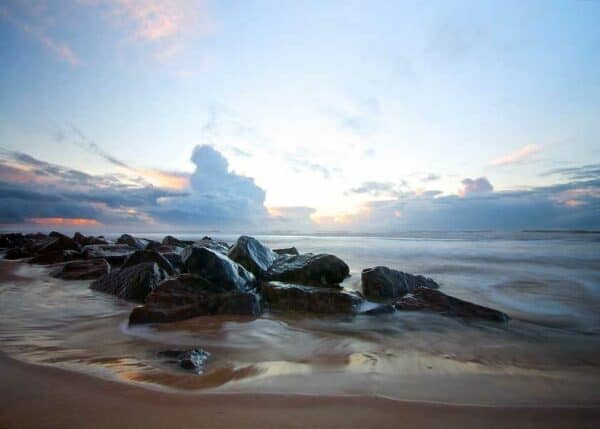 De smukke blanke sten i strandkanten fanger det sidste lys fra den nedgående sol, bølgerne tegner drømmeagtige billeder med havets skum