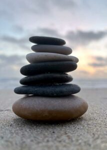 Stakkede Zen sten på stranden balancerer smuk i solens sidste stråler på stranden