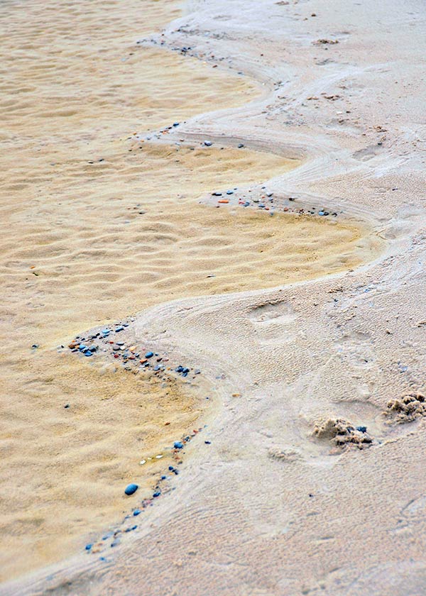 Forunderlige mønstre i sandet på stranden, vand, sten og sand i flot sammenspil