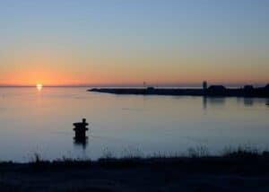 Solen stiger op i øst og maler horisonten rød, mens fjorden er spejlblank og alt ånder ro.