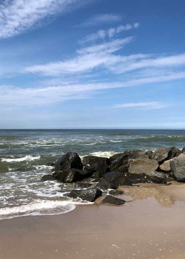 Bølger løber sagte mod land og rundt om bølgebryder, eller høfterne langs stranden