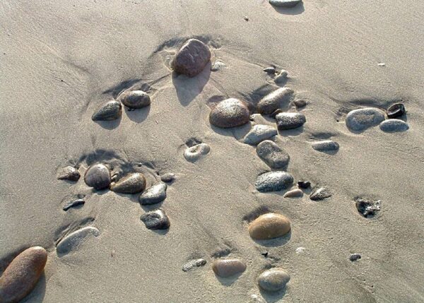 Sten i sandet på stranden tegner fantastiske mønstre efter vandet har trukket sig tilbage