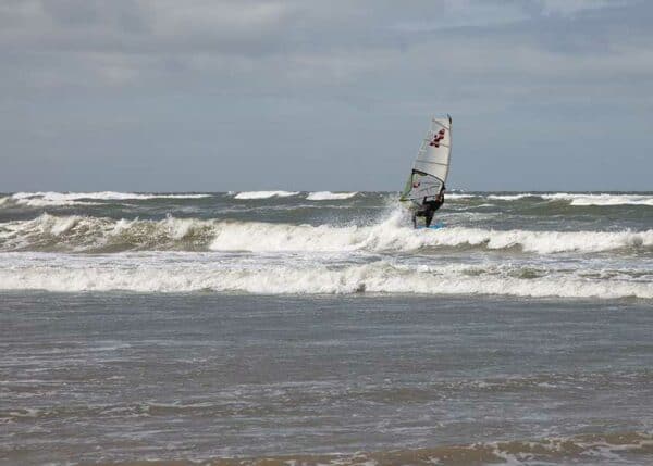 Vindsurferen har netop fået vind i sejlene og styr mod bølgerne længere fra kysten.